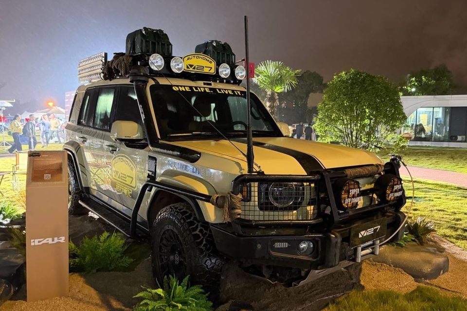 Yellow iCaur V27 customised overseas display car, identified by its V27 plate and roof sign, with bull bar, raised air intake, roof cargo and auxiliary lights; these accessories are not confirmed Australian standard equipment.