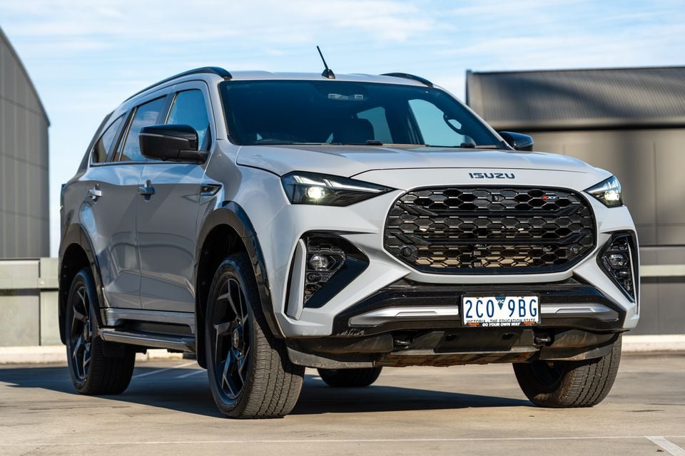 A silver 2026 Isuzu MU-X X-Terrain SUV seen from the front-left, parked on a concrete surface with black trim accents and alloy wheels.