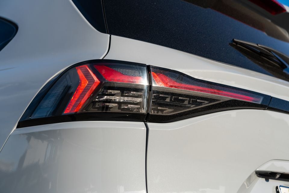 Close-up of the LED tail light on a white 2026 Isuzu MU-X X-Terrain SUV, showing arrow-shaped red light elements and smoked lens detail