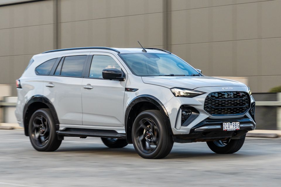 A silver 2026 Isuzu MU-X X-Terrain SUV seen from the front-side while driving in an urban area
