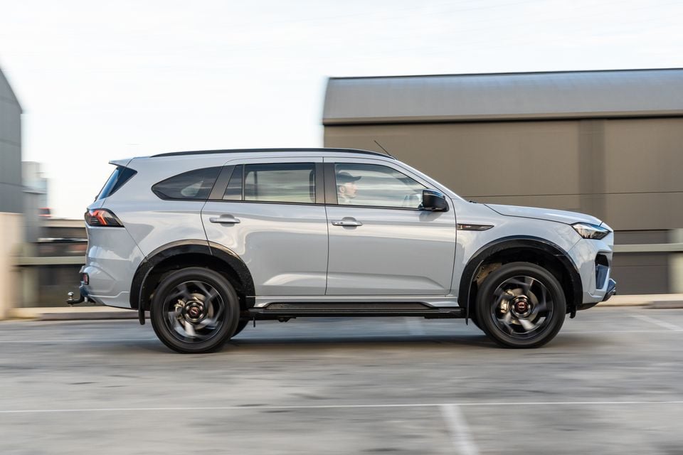 A silver 2026 Isuzu MU-X X-Terrain SUV seen from the side while driving on a road