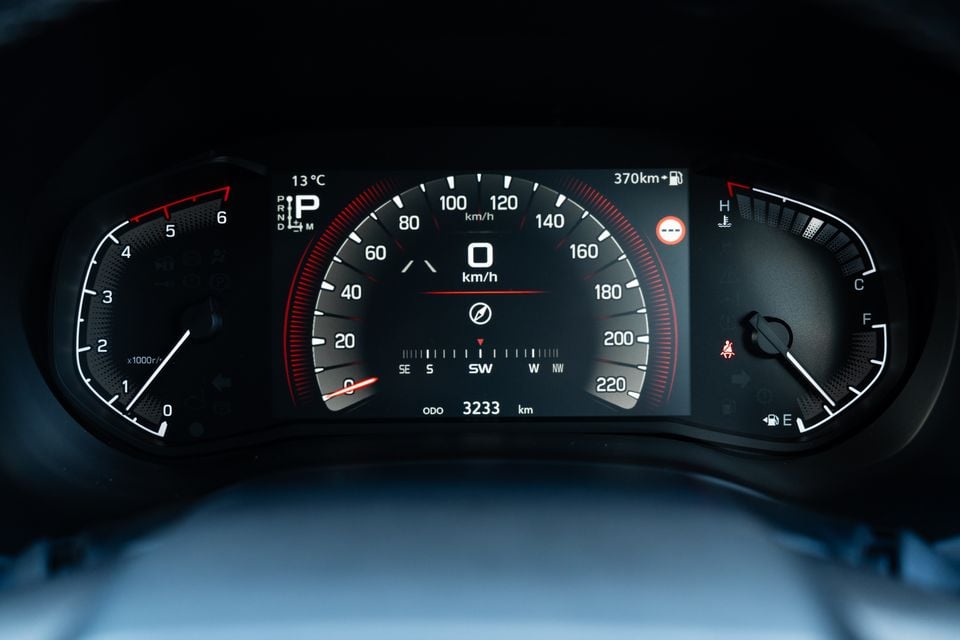 Close-up of the digital instrument cluster in a 2026 Isuzu MU-X X-Terrain, showing a speedometer, tachometer, compass, odometer reading of 3233km and 370km of remaining range.