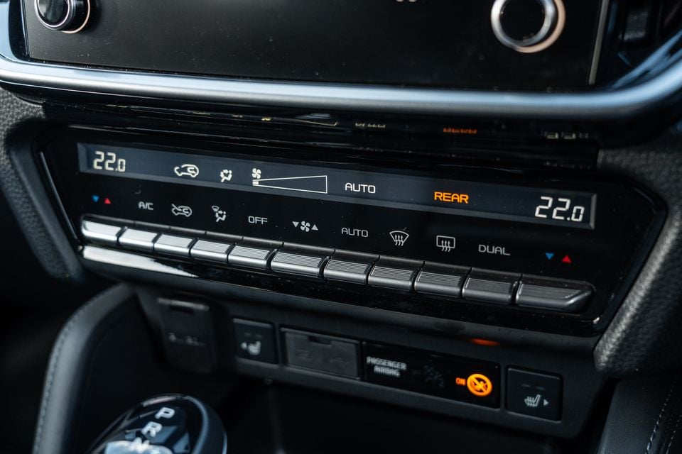 Dual-zone climate control panel of a 2026 Isuzu MU-X X-Terrain, showing temperature displays set to 22 degrees on both sides, AUTO fan control, and rear demister buttons