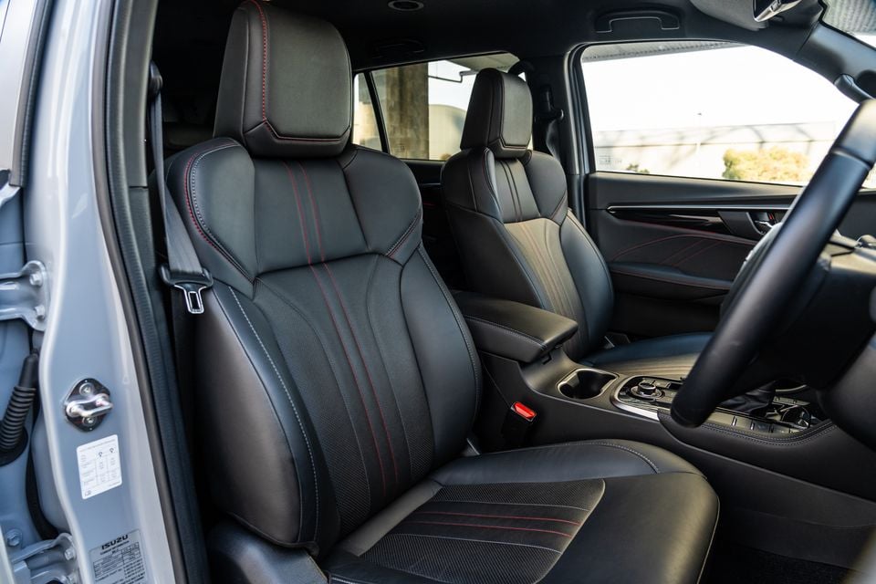 Black leather front seats with red stitching inside a 2026 Isuzu MU-X X-Terrain, viewed from the open driver's door