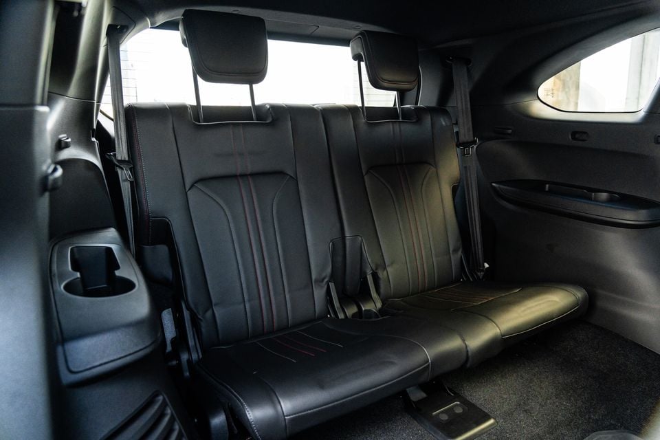 The rear bench seat of a 2026 Isuzu MU-X X-Terrain, trimmed in black leather with red contrast stitching and a centre cup holder armrest