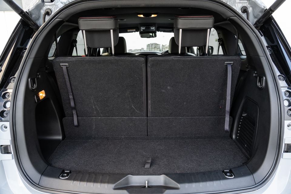 The empty boot of a 2026 Isuzu MU-X X-Terrain SUV, showing the carpeted cargo area with rear seats upright and tailgate open.