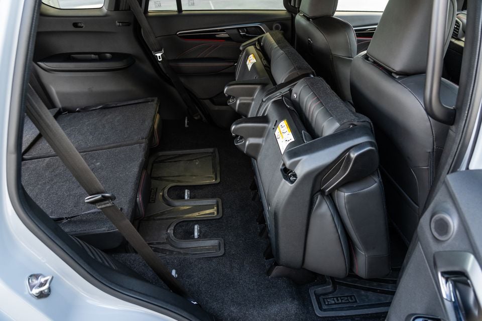 Rear seats folded flat inside the Isuzu MU-X, showing the expanded cargo area with child seat bases stored inside the cabin