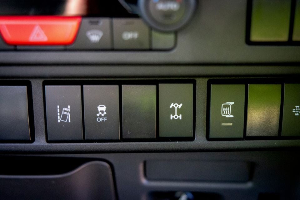 Close-up of dashboard switches in a 2026 Isuzu NMS truck, including hazard lights, traction control and differential lock buttons