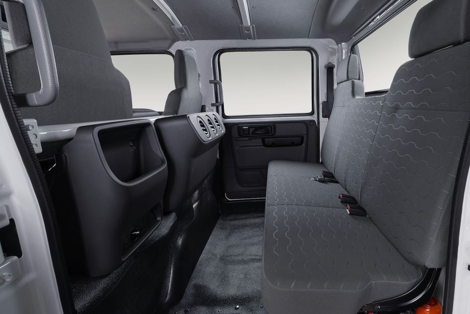 The rear crew cab interior of a 2026 Isuzu NMS 45-150 AWD truck, showing a bench seat and side-facing jump seats
