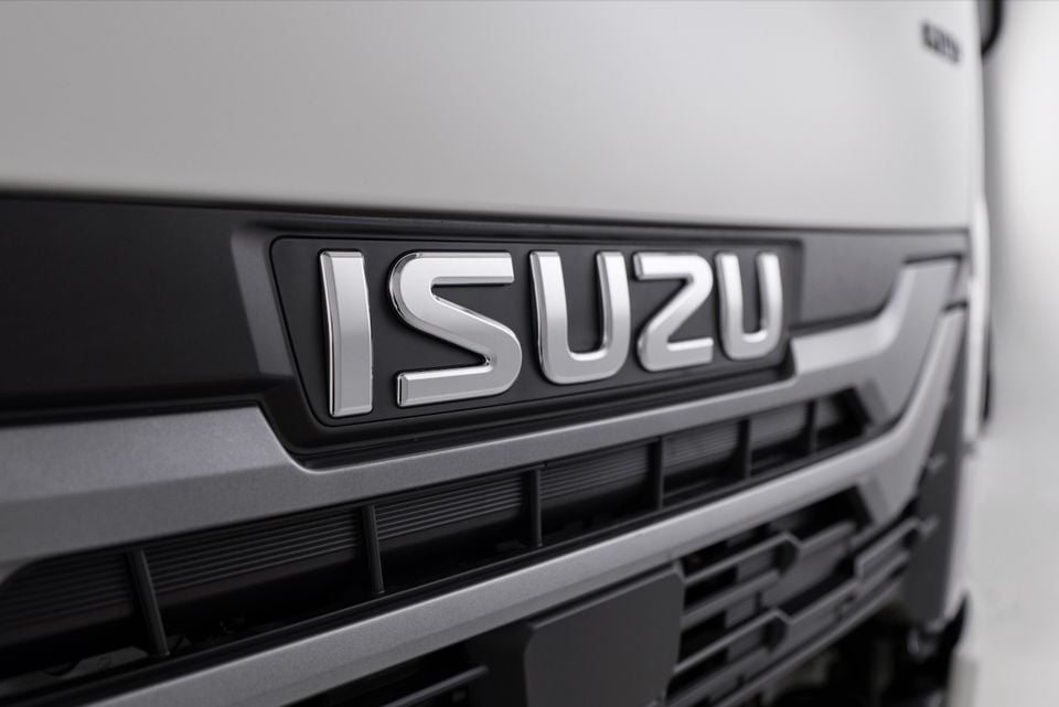 Close-up of the Isuzu badge on the front grille of a 2026 Isuzu NMS truck