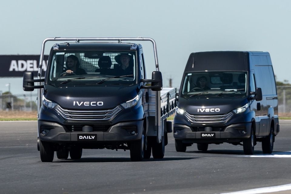 Two Iveco Daily commercial vehicles — a flat-bed cab-chassis and a high-roof van — driving on a circuit at Adelaide