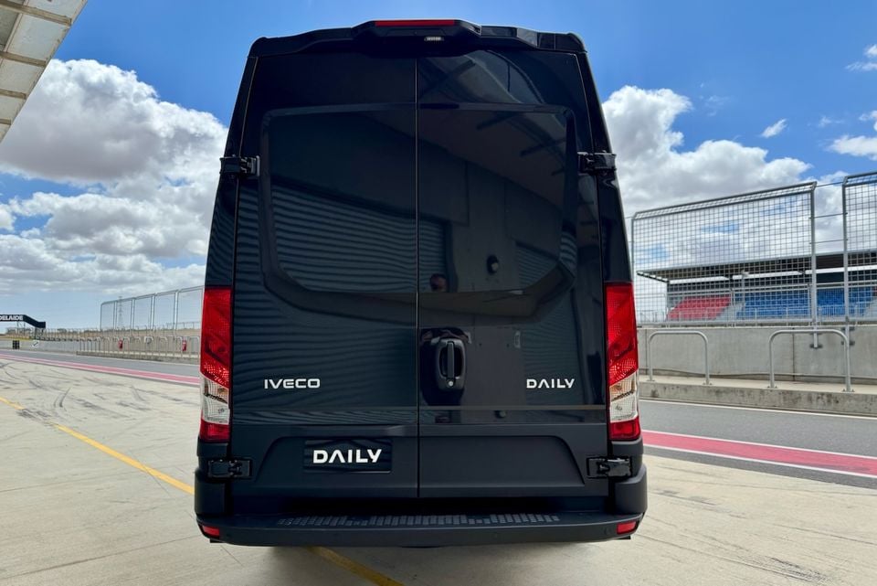 Rear view of a black Iveco Daily van at a motorsport circuit