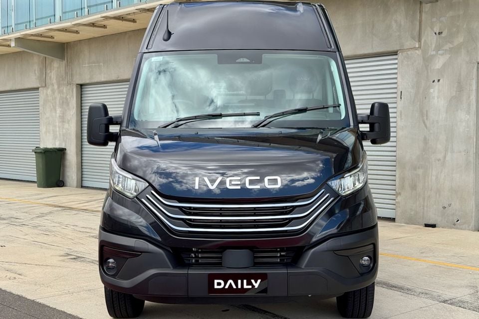 Front view of a dark-coloured Iveco Daily van parked in a concrete outdoor area