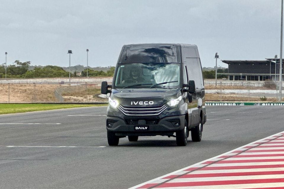 An Iveco Daily van driving on a motor racing circuit, seen from the front