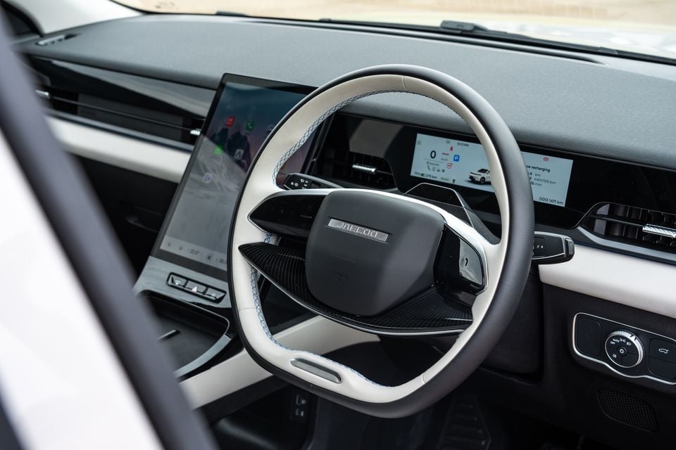 Interior of the 2026 Jaecoo J5 EV showing the two-tone white and black steering wheel, central touchscreen infotainment display, and digital instrument cluster