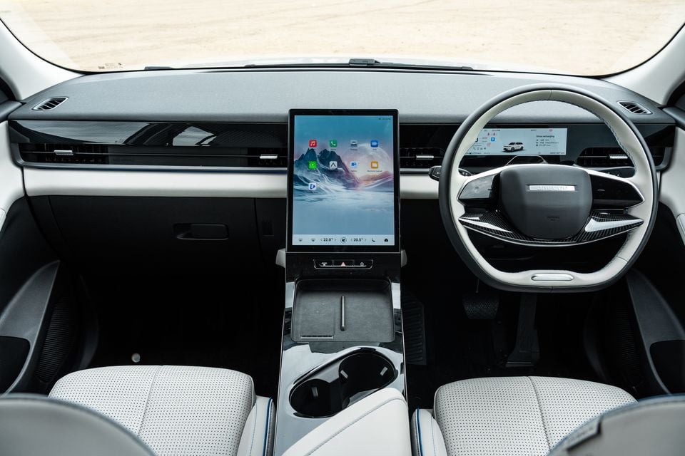 Interior of the 2026 Jaecoo J5 EV showing the dashboard, large central touchscreen infotainment display, digital instrument cluster, steering wheel, and light grey front seats