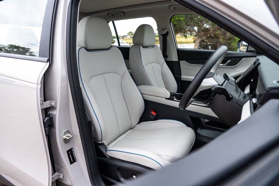 Light grey leather front seats with blue contrast stitching inside a 2026 Jaecoo J5 EV, viewed through the open driver's door