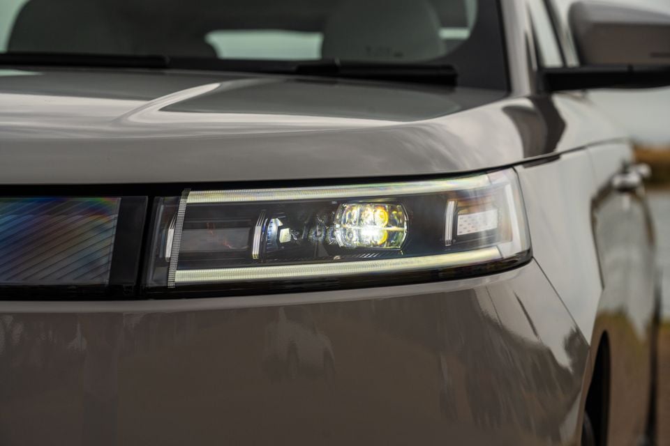 Close-up of the LED headlight on a grey 2026 Jaecoo J5 EV, showing detailed lamp internals and daytime running light strip.