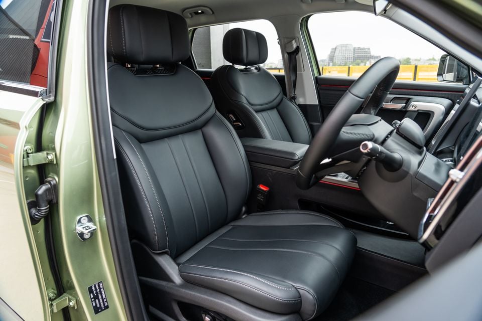 Black leather front seats and steering wheel inside a 2026 Jaecoo J7, viewed from the open driver's door