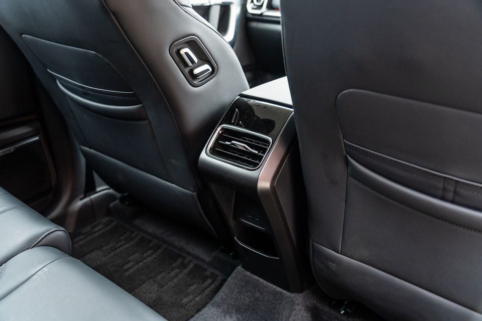 Rear interior of the 2026 Jaecoo J7 showing the back of the front seat with a seat adjustment lever, rear air vent, and dark leather upholstery