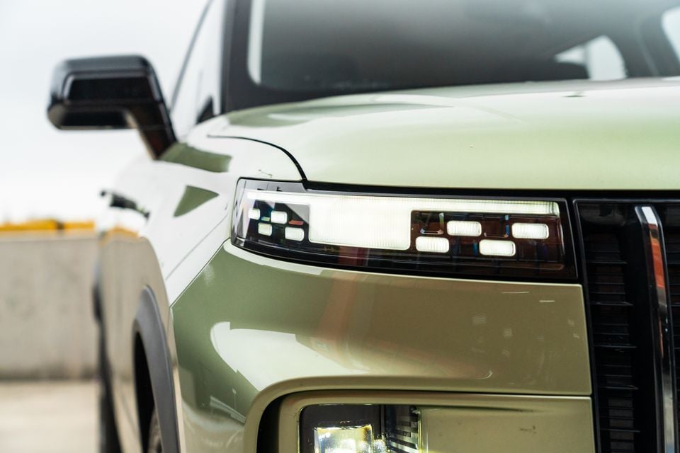 Close-up of the LED headlight and front corner of a light green Jaecoo J7 SUV