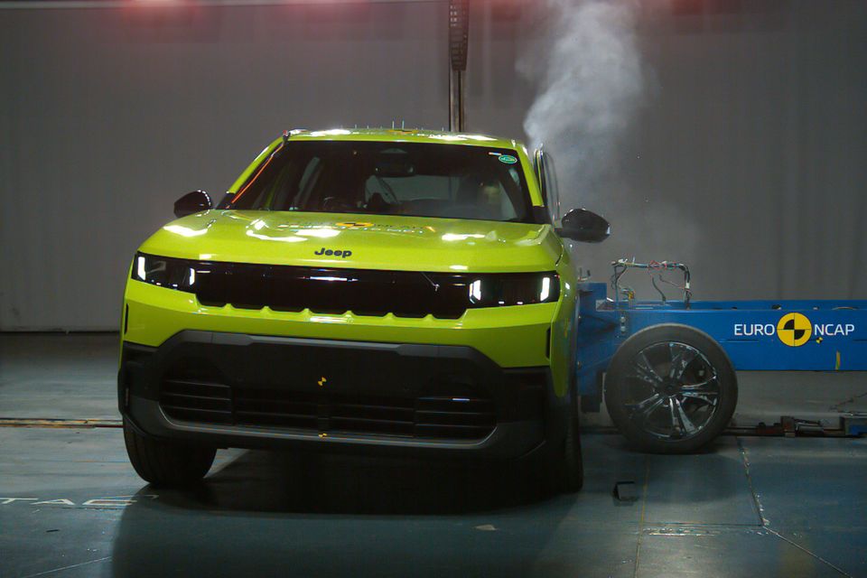 A yellow-green 2026 Jeep Compass SUV undergoing a Euro NCAP side pole crash test in a safety testing facility