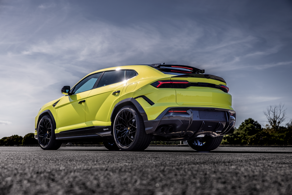 A yellow-green Lamborghini Urus Performante SUV seen from the rear three-quarter angle, showing its aggressive bodykit, large spoiler, and dark alloy wheels.