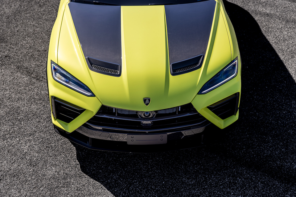 Front-overhead view of a yellow-green 2026 Lamborghini Urus Performante with carbon fibre bonnet accents, seen from above on a paved surface.