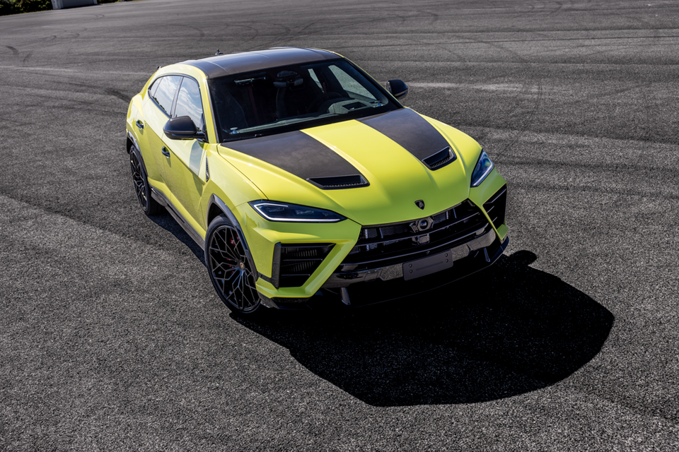 A yellow-green 2026 Lamborghini Urus Performante SUV seen from a high front angle on a track surface, featuring a carbon fibre bonnet and aggressive body kit