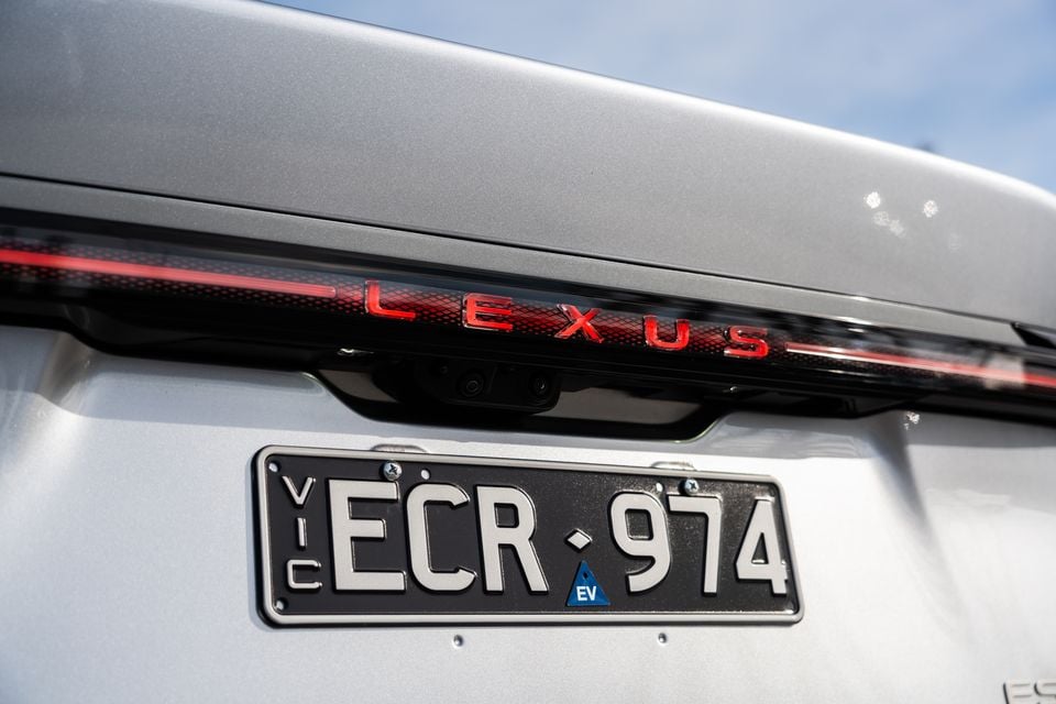 Close-up of the rear of a silver 2026 Lexus ES350e showing the illuminated Lexus lettering, rear camera, and Victorian EV number plate