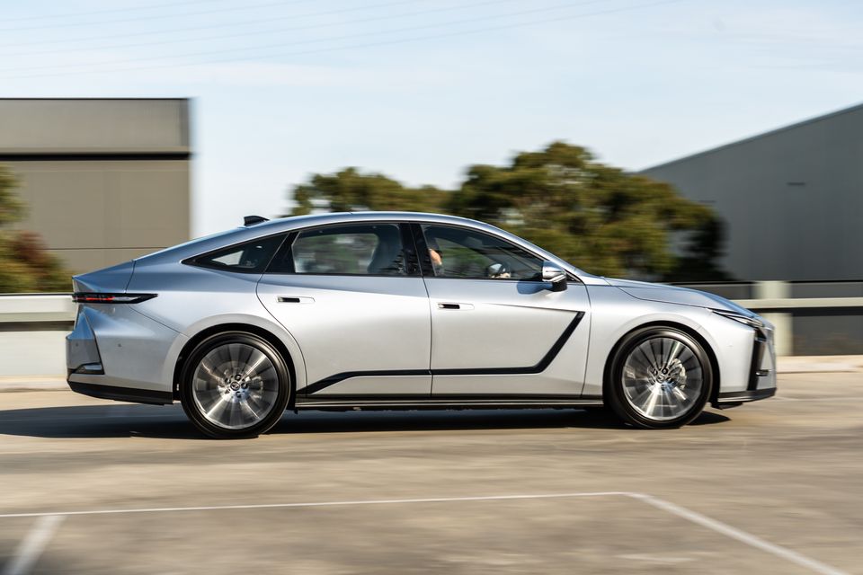 A silver 2026 Lexus ES 350e sedan seen from the side while driving on a road