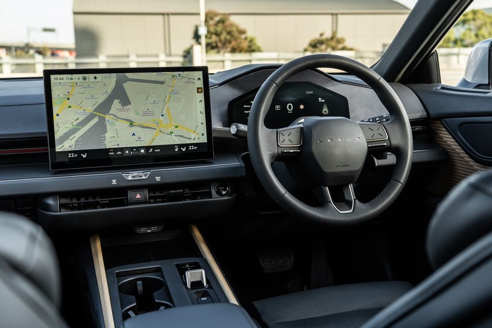 Interior of a Lexus ES showing the large touchscreen infotainment display with navigation, steering wheel with Lexus badge, digital instrument cluster, and centre console
