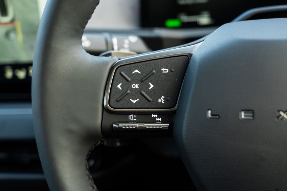 Close-up of the Lexus ES steering wheel controls, showing navigation, media, and voice command buttons on the left spoke