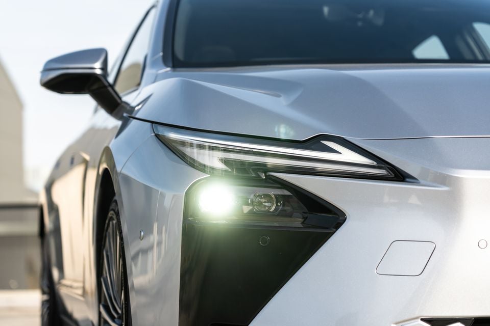 Close-up of the front headlight and bonnet of a silver 2026 Lexus ES 350e, showing the illuminated LED headlight and sharp angular styling.