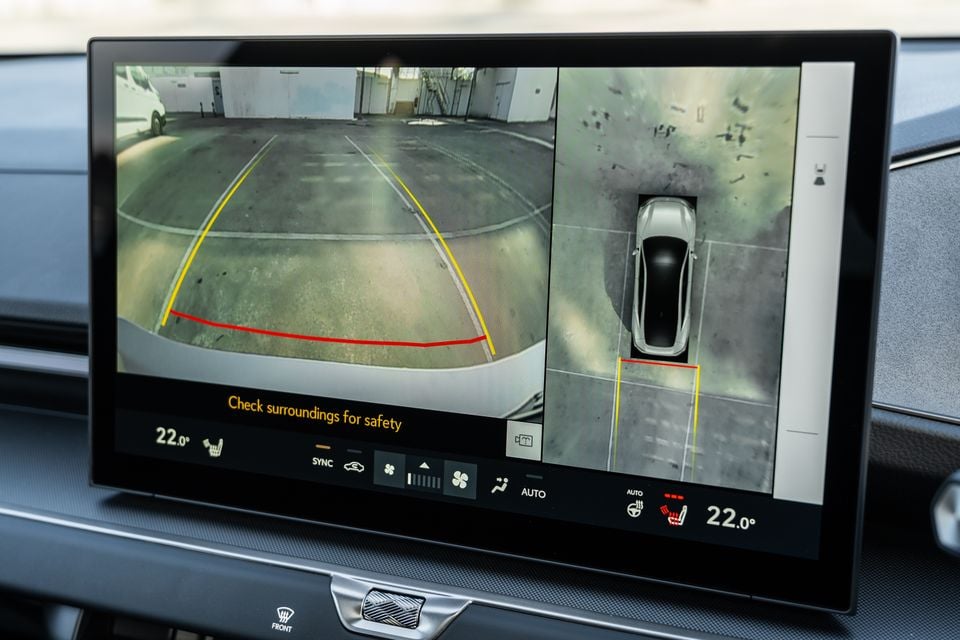 The infotainment touchscreen of a Lexus ES350e displaying the reversing camera view alongside a 360-degree surround-view camera display, with a safety warning message and climate control settings visible.