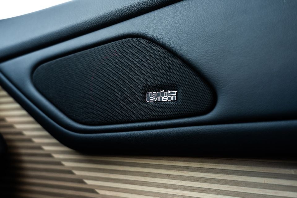 A Mark Levinson speaker grille on the door panel of a 2026 Lexus ES350e, with wood-look trim visible below.