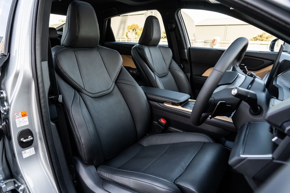 Black leather front seats of a 2026 Lexus ES350e, viewed from the open driver's side door, showing the centre console and steering wheel