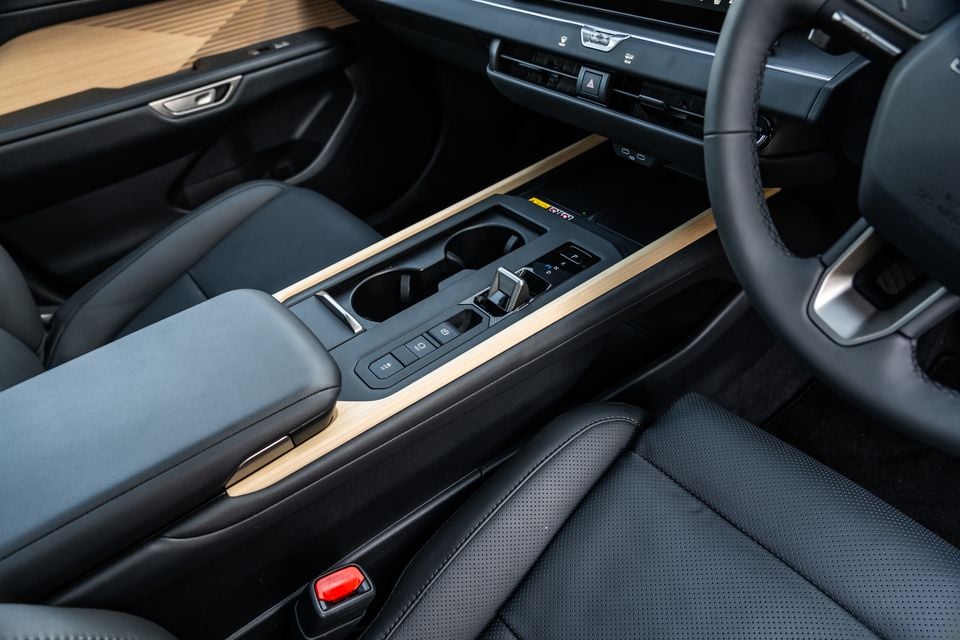 Interior view of the 2026 Lexus ES 350e Sports Luxury showing the centre console with wood trim, cup holders, gear selector, and dark leather upholstery