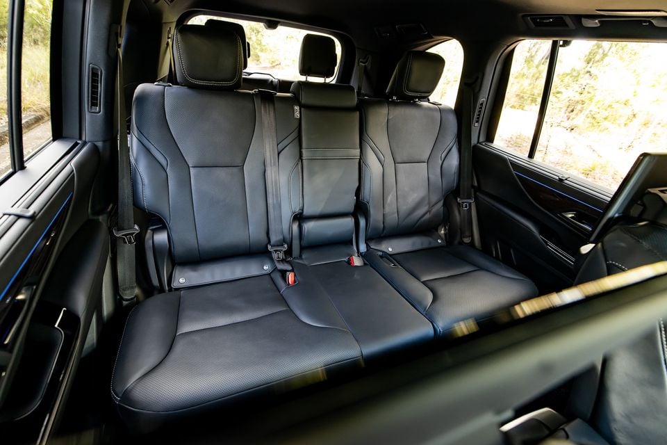 Rear seats of a 2026 Lexus LX700h Sports Luxury SUV, showing a three-seat black leather bench with perforated upholstery, white contrast stitching, and individual headrests