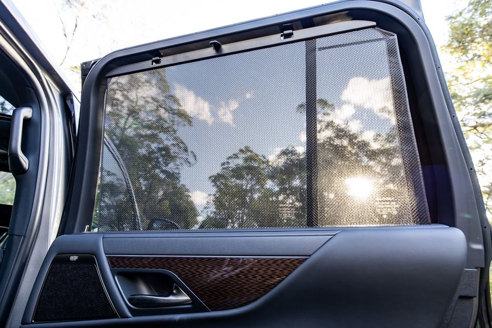 A rear door sun shade blind extended across the window of a Lexus LX, with a wood-trimmed door panel visible below