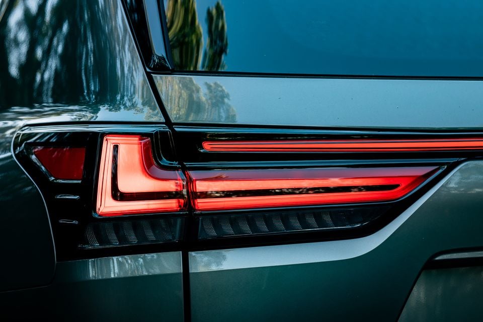 Close-up of the LED tail light on a dark green 2026 Lexus LX700h Sport Luxury, showing a wraparound light bar extending across the tailgate