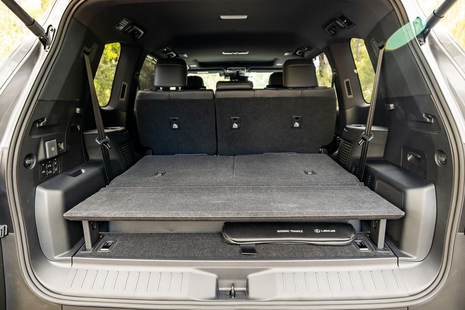 Boot area of a Lexus LX700h Sport Luxury SUV with the third-row seats folded and a sliding load floor extended, showing under-floor storage with a Lexus warning triangle compartment