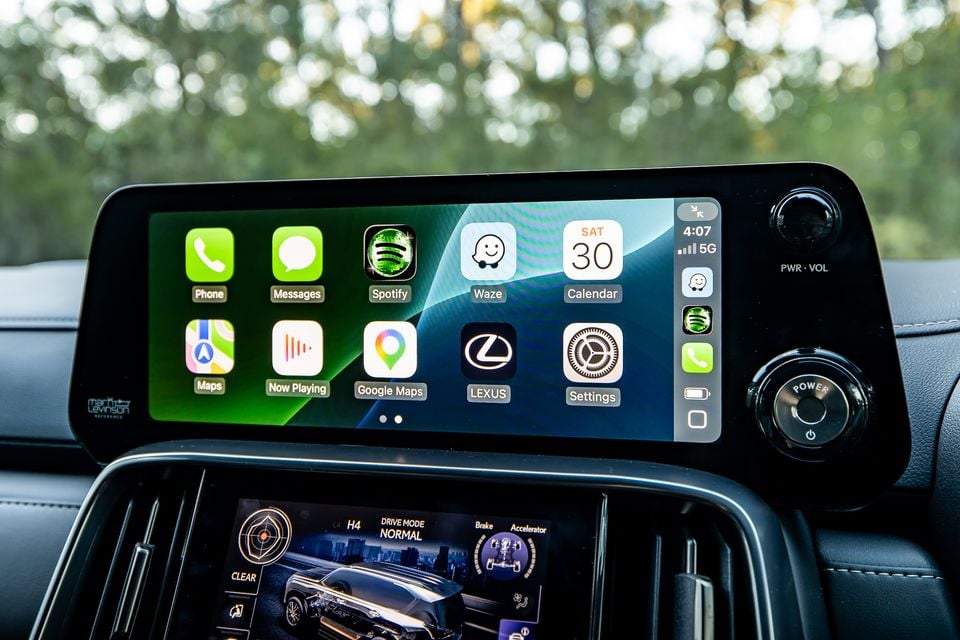 Apple CarPlay interface displayed on the Lexus LX infotainment screen, showing apps including Phone, Messages, Spotify, Waze, Google Maps and Settings, with a secondary driver display screen visible below