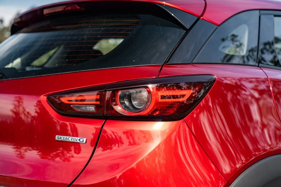 Close-up of the rear tail light on a red Mazda CX-3 SUV, showing the SkyActiv-G badge