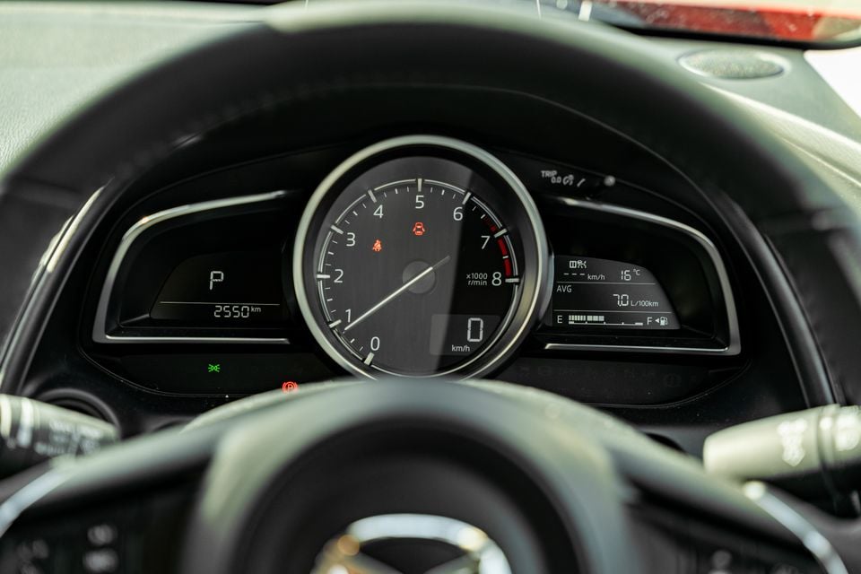 Mazda CX-3 instrument cluster showing tachometer, odometer reading 2550km, gear selector in Park, and a multi-information display with fuel economy and temperature readings