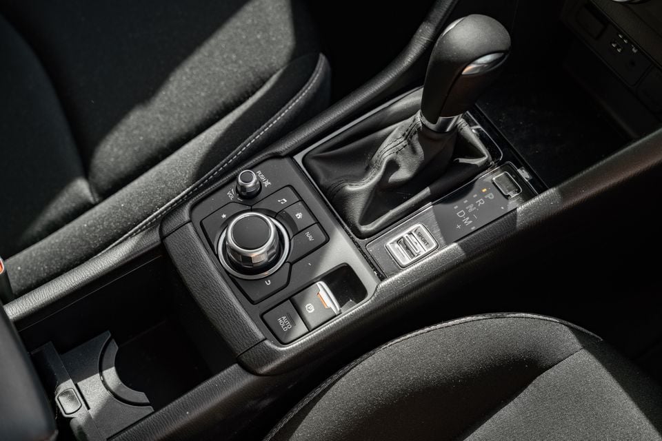 Centre console of a Mazda CX-3 showing the gear shifter, rotary infotainment controller, auto hold button, and sport mode switch