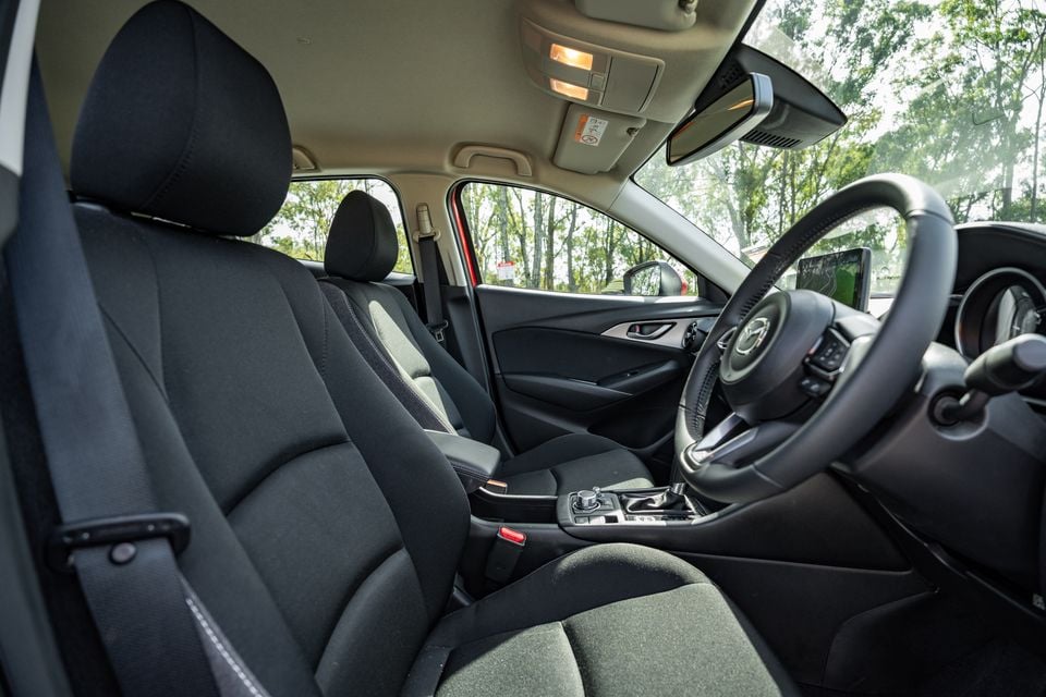 Interior view of a Mazda CX-3 showing the front seats, steering wheel, centre console and infotainment screen