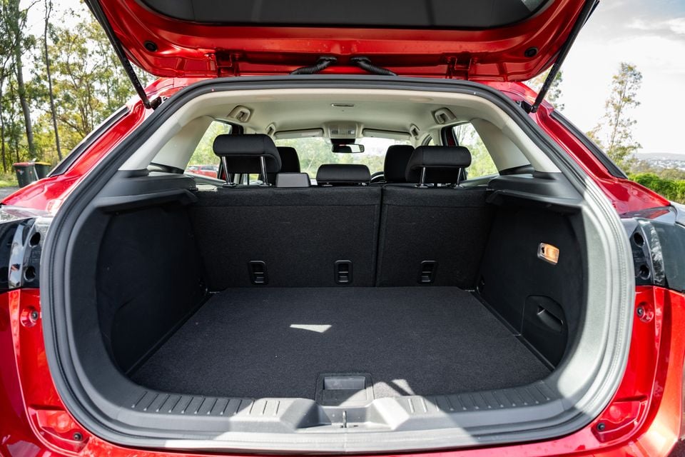 Open boot of a red Mazda CX-3 SUV showing a spacious, empty cargo area with the rear seats visible through the cabin