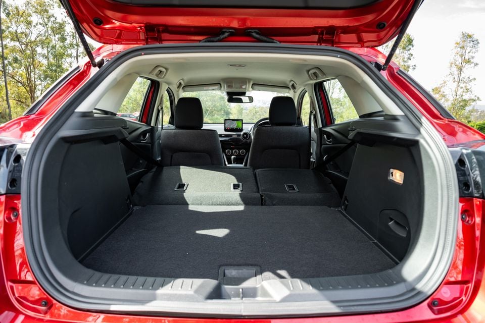 Boot of a red 2026 Mazda CX-3 SUV with rear seats folded flat, showing a large extended cargo area with the tailgate open