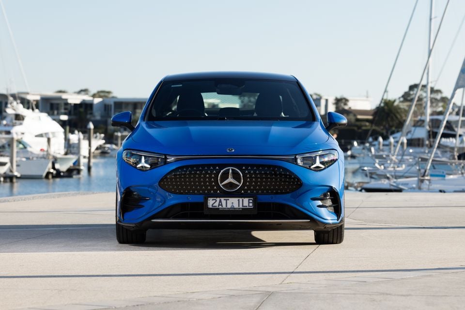 A blue 2026 Mercedes-Benz CLA 250 Electric seen from the front, parked at a marina